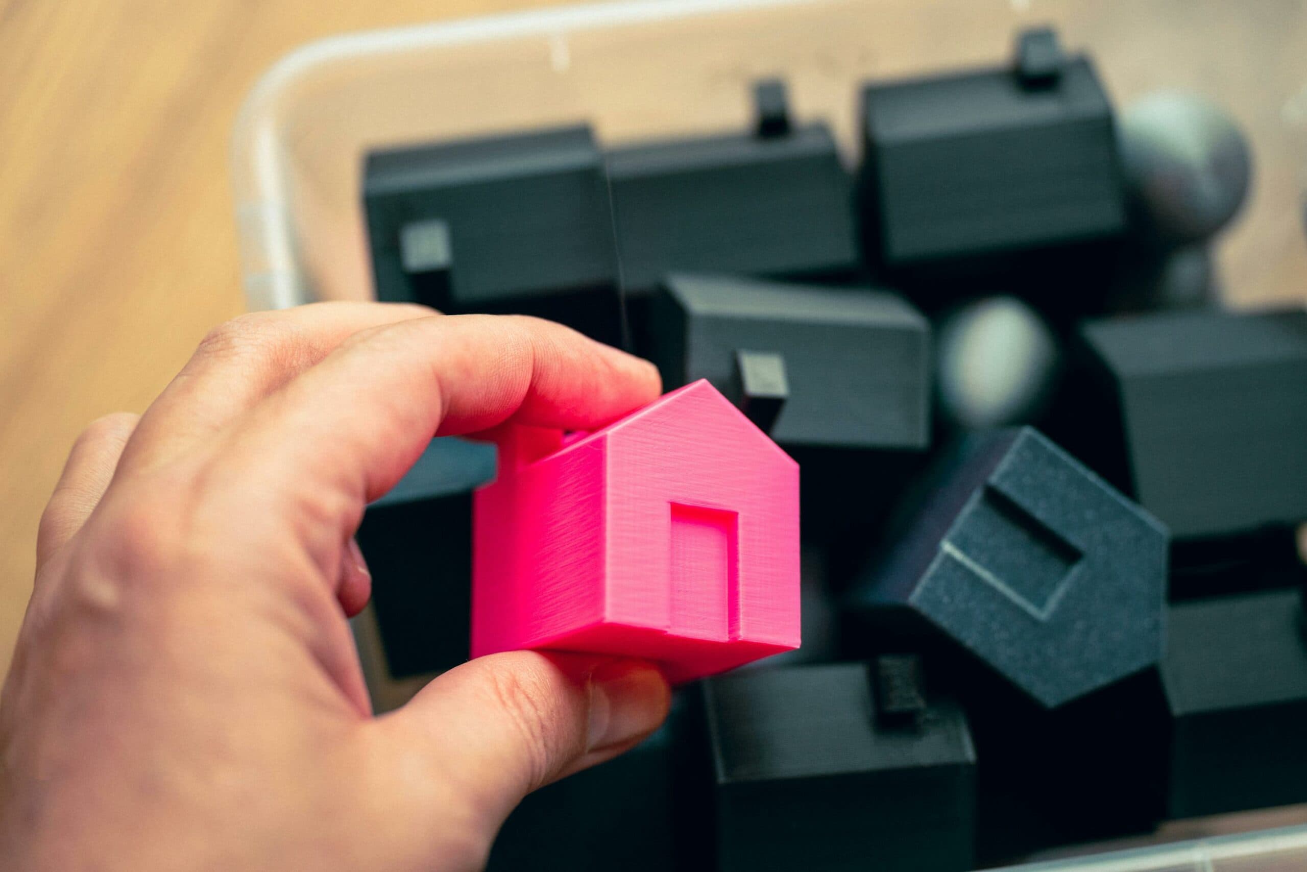 Home Equity Loan – Your Funds for Any Purpose Hand holding a pink house model among black blocks – a metaphor for a home equity loan and property-based financing